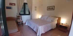 罗萨诺La Piana degli Ulivi的卧室配有床、椅子和窗户。
