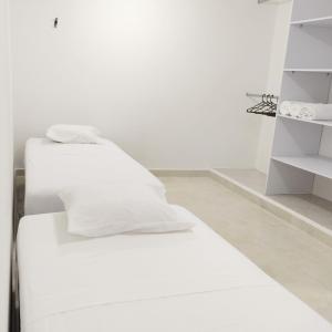 里奥阿查Apartamentos Riohacha的白色墙壁客房的两张床