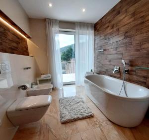 布尔诺Nobless Apartments Holedná Brno的一间带大型白色浴缸和卫生间的浴室