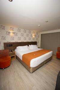 佩雷拉兹万豪华酒店的一间卧室配有一张大床和一张橙色椅子