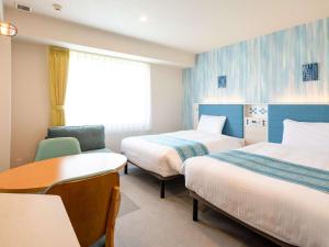 石垣岛Comfort Hotel Ishigaki Island的酒店客房设有两张床和一张桌子。