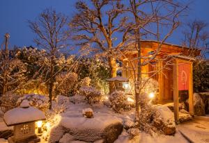 高山Ichinomatsu Japanese Modern Hotel的花园在晚上被雪覆盖,灯光照亮