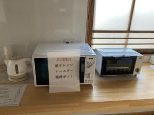 沼津沼津ライダーハウスしんちゃん的桌子上设有微波炉和烤面包机。