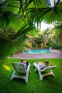 BolivarHighway 1 Holiday & Lifestyle Park的两人坐在游泳池附近的草坪椅上