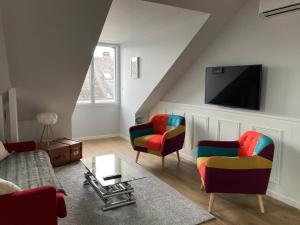 布鲁瓦3 Appartements SCI Jape的客厅配有色彩缤纷的椅子和平面电视。