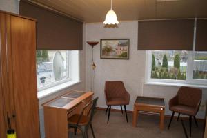 库雷萨雷Nooruse Majutus的一间设有椅子和书桌的等候室和两个窗户
