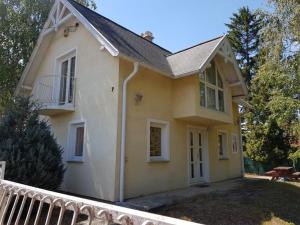 利波特Tóparti Vendégház - Lipót, Magyarország的黄色的小房子,设有门廊和阳台