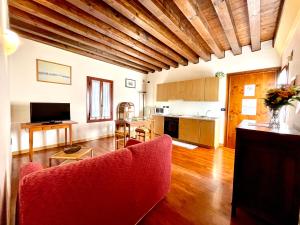 普雷甘齐奥尔Alla Barchessa di Villa Querini的一间带红色沙发的客厅和一间厨房