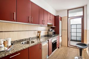 普拉亚布兰卡Villa Beatrice的一间带红色橱柜和水槽的厨房