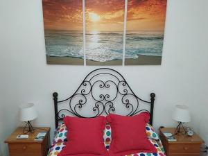 加的斯Los Tres Girasoles的一间卧室配有一张带红色枕头的床和两盏灯。