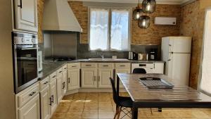 Saint-André-dʼAllasGrand Gite La Salamandre Proche Sarlat de 1 à 10 personnes的厨房配有白色橱柜和桌子