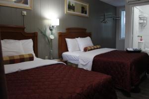 帕里桑德Sunrise Inn的酒店客房,配有两张带红色床单的床