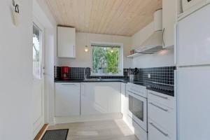 蒙克博Dejlig feriebolig med havudsigt i naturskønt område的白色的厨房配有白色橱柜和窗户