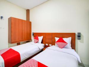 棉兰OYO 90341 Sean's Residence的一间卧室配有两张带红白色枕头的床