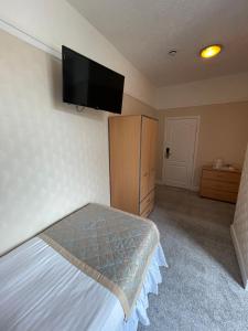 斯凯格内斯Queens Hotel, Skegness的卧室配有一张床,墙上配有电视。