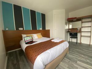 Parçay-Meslay北图尔法斯特酒店的一间卧室配有一张带笔记本电脑的床