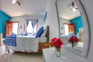 阿布拉奥Suites Casa Azul-Vila do Abraão- conforto, limpeza, ótima localização的一间设有床、镜子和鲜花的客房