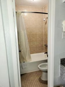 橙县最佳价格套房汽车旅馆的带浴缸、卫生间和淋浴的浴室。