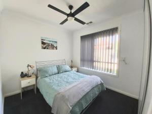 LargsLovely Modern 3br 2bth Beachside suburb Home的一间卧室配有一张床和吊扇