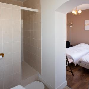 Rozoy-sur-Serre恩特雷里奥斯酒店的一间带步入式淋浴间的浴室,位于床边