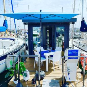 阿尔盖罗Houseboat Seabreeze的一个带蓝伞的码头上的桌椅