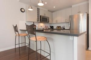 北温哥华Lower Lonsdale Aprtment的厨房配有2个吧台凳和不锈钢冰箱