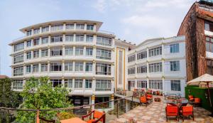 加德满都Durbar Hotel & Residence的一座白色的大建筑,前面摆放着橙色椅子