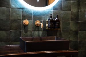 惠灵顿The Intrepid Hotel的浴室水槽和墙上的两瓶葡萄酒