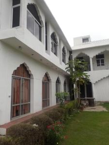 珀勒德布尔Vamoose Raj Palace的白色的建筑,设有窗户和绿色的院子
