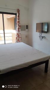 波戈马洛Saritas Guest House - Bogmalo Beach的一间配有电视的房间里一张大白色的床