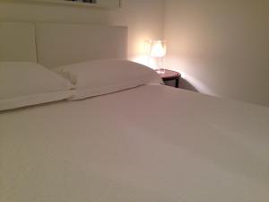 奥斯图尼Villa Masai的一张带白色床单的床和一张桌子上的台灯