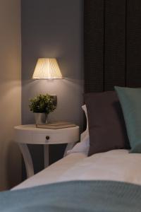 MiazzinaHotel Milano & Apartments的一张带床头柜的床铺,配有一盏灯和一张白色的床