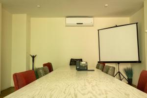 科米坦德多明格斯Hotel Nak'An Secreto Maya的一间会议室,配有桌椅和白板