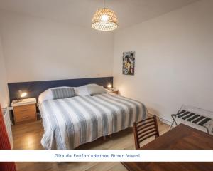 巴里吉斯Gîte de Fanfan的一间卧室配有一张带条纹毯子的床和一张书桌
