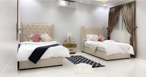 艾卜哈مساكن الدار 1的卧室内的两张床,配有白色的墙壁和粉红色的枕头