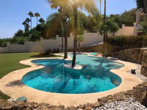 EsteponaHuge Golf and Spa Mansion 8 min from Puerto Banus的庭院里棕榈树的游泳池