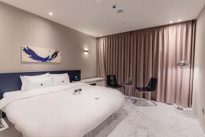 金海市Zam101 Hotel Gimhae的酒店客房带大型白色床和椅子