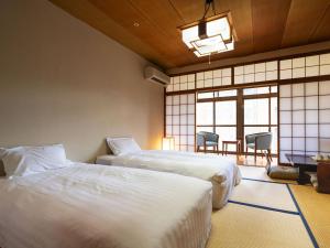 谏早市Hotel Flags Isahaya Nagasaki的一间卧室配有两张床和一张桌子及椅子