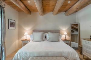 奥佩德Domaine Les Roullets的一间卧室配有一张带白色床单和木制天花板的大床。