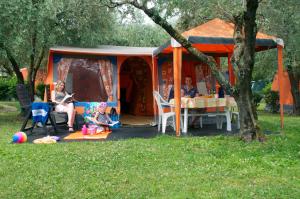 加里波第港Casa Mobile - Spiaggia e Mare Holiday Park的一群人坐在帐篷里的桌子上