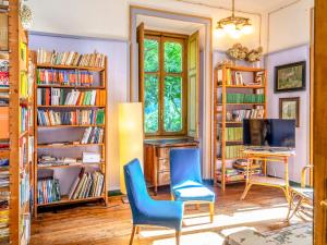 Ala di SturaHoliday Home Villa Biino - VIZ200 by Interhome的一间设有两张蓝色椅子、书桌和书架的房间