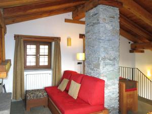 桑佩伊雷Chalet Casot Pra Viei - SMY100 by Interhome的客厅配有红色沙发,设有石柱