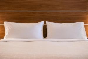 甘尼森甘尼森智选假日酒店&套房的一张带两个白色枕头和木制床头板的床