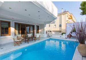 雅典Villa Ariadne的房屋设有1个带桌椅的游泳池