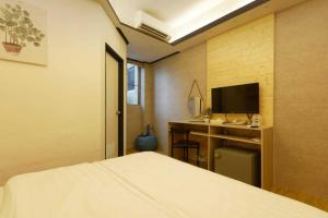台南府城商旅文创新馆的一间卧室配有一张床和一张书桌及电视