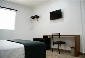 蒙克洛瓦Hotel Capital Frontera的一间卧室配有一张床、一把椅子和电视。
