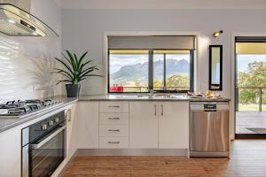 West Kentish曼娜山农家乐的厨房配有白色橱柜、水槽和窗户。