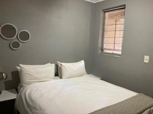比勒陀利亚Guesthouse @ 31 Murray的一间卧室配有一张带白色床单的床和一扇窗户。