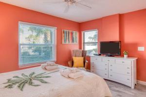巴特勒海滩Driftwood Escape的一间卧室设有橙色的墙壁和一张带电视的床。