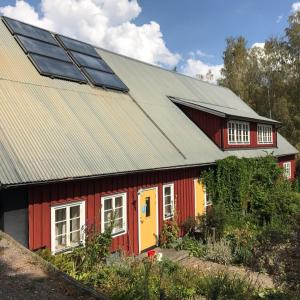 LinghemKlefstad Gård的一座红色和黄色的房子,上面有太阳能电池板